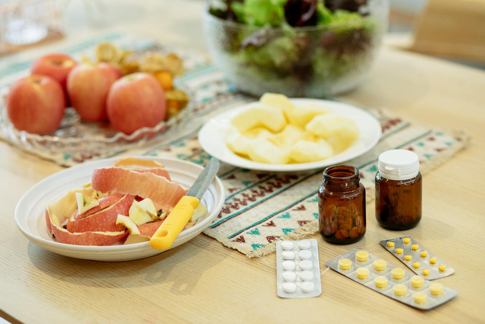 Fresh ripe fruits and pills placed on table at home